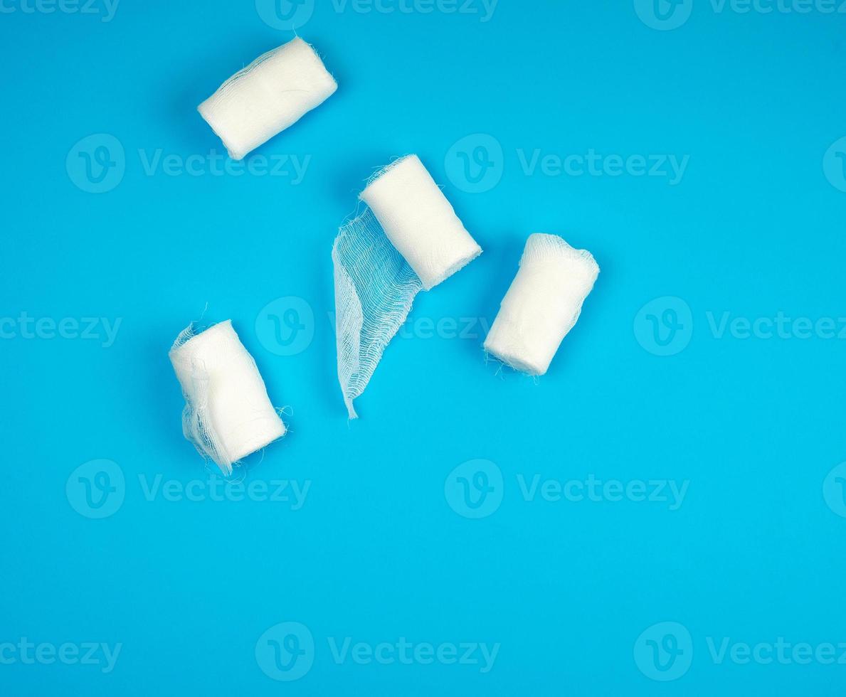 rolled up white sterile medical bandages on a blue background photo