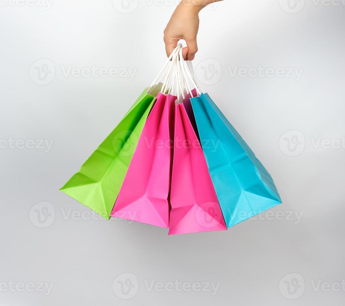 female hand holding four colored paper shopping packaging bags photo