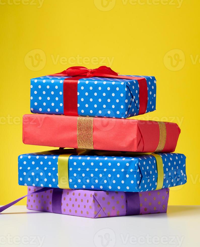 a stack of gift boxes tied with a ribbon on a yellow background photo