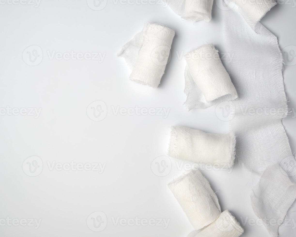 rolled up white sterile medical bandages on a white background photo