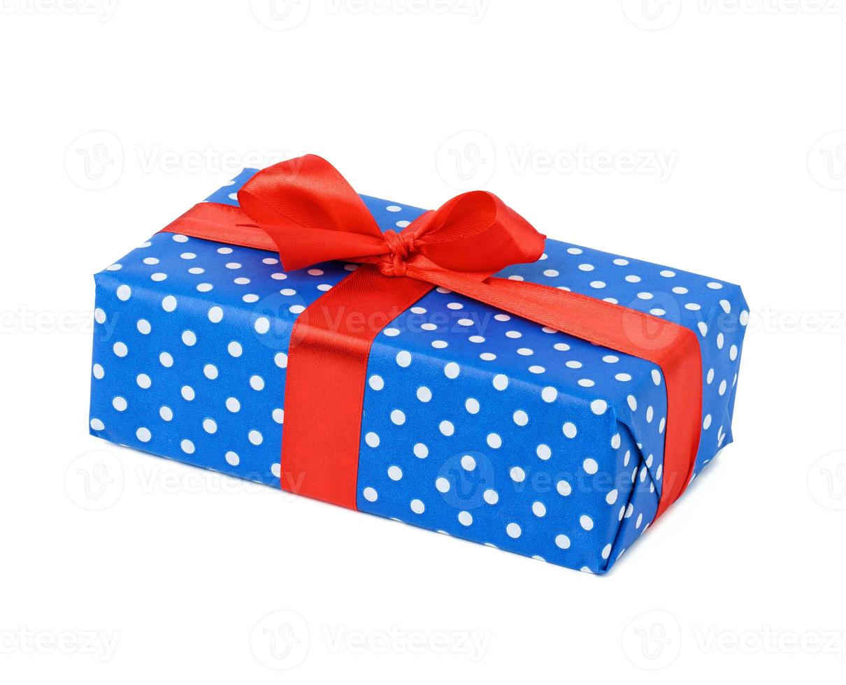 box wrapped in blue polka dot paper and tied with a red silk ribbon on a white background, photo