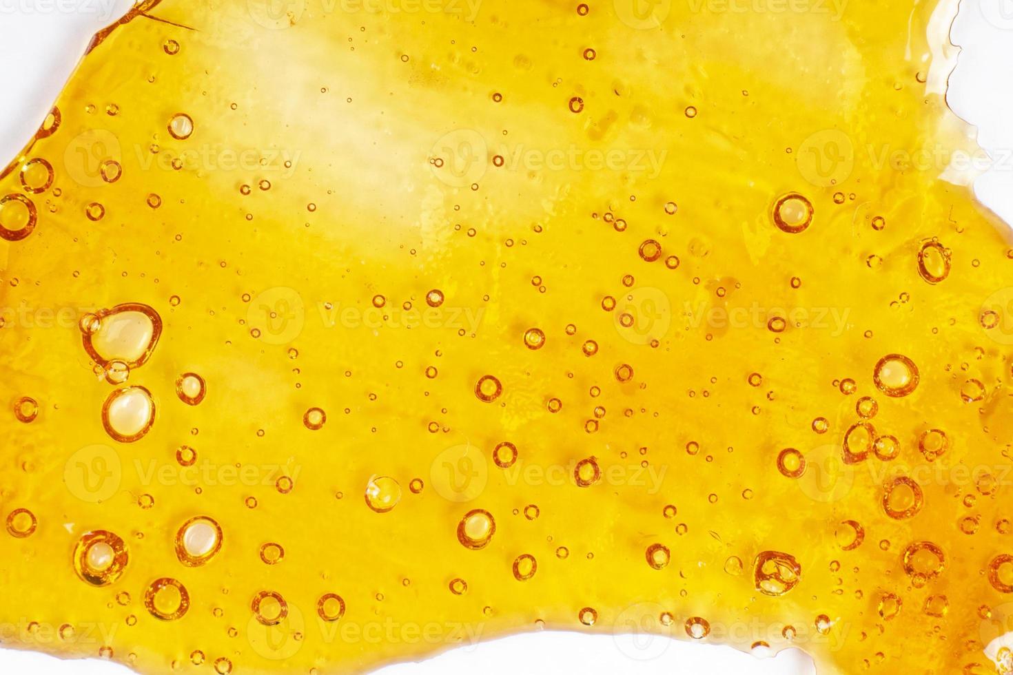 strong extract of gold cannabis wax with high thc close up, bubble shatter texture on paper photo