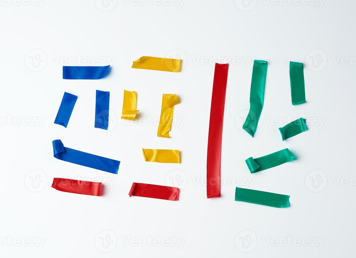 set of torn multicolored rubber pieces of electrical tape glued to a white background photo