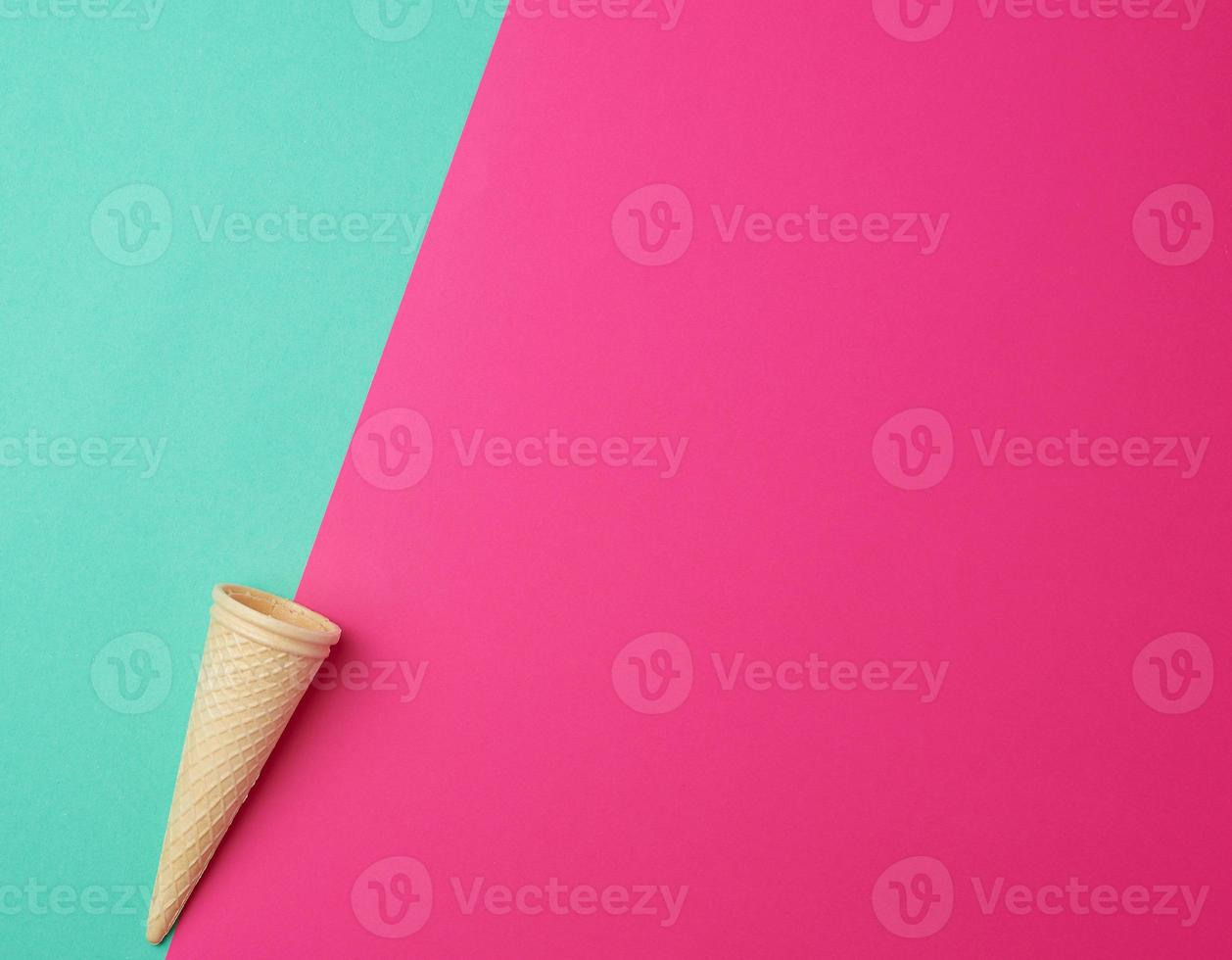 empty conical baked waffle cup on a green-pink background, place for text photo