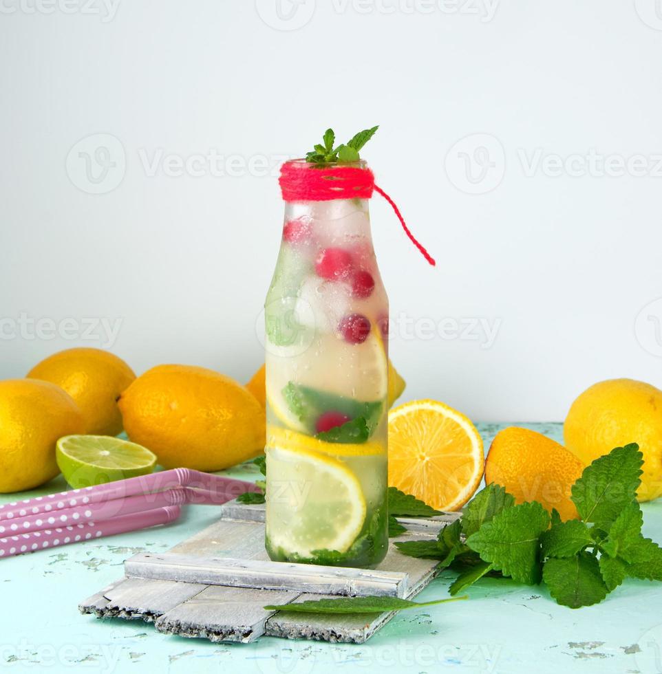 summer refreshing drink lemonade with lemons, cranberry, mint leaves, lime in a glass bottle photo