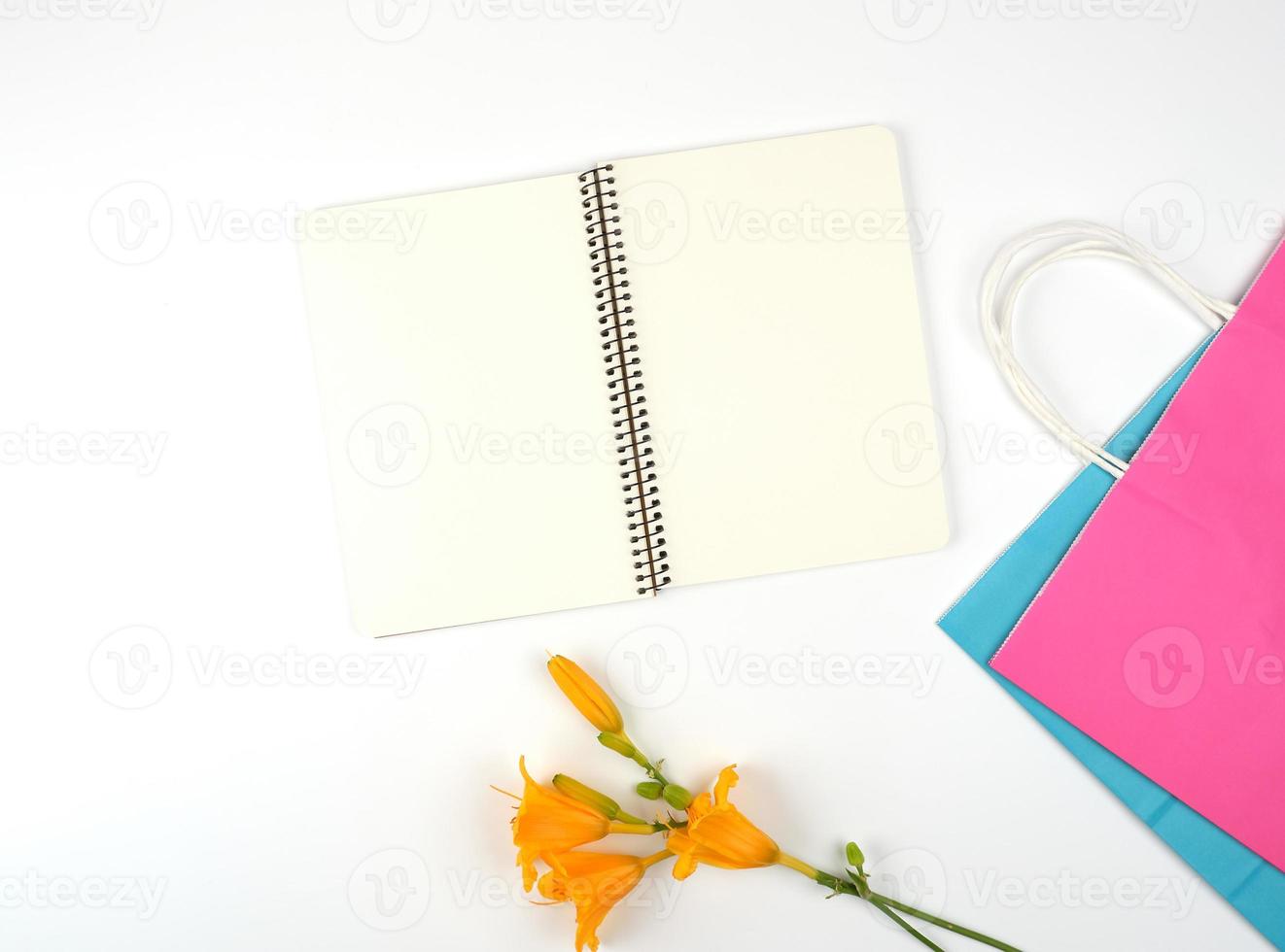 open notebook with blank white sheets and multi-colored paper shopping bags photo