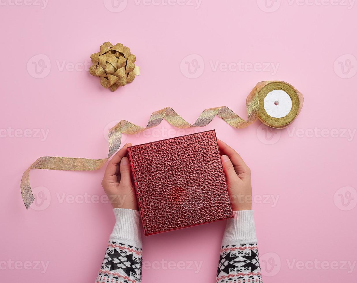 female hand holds a red box and golden ribbon, concept of congratulations photo