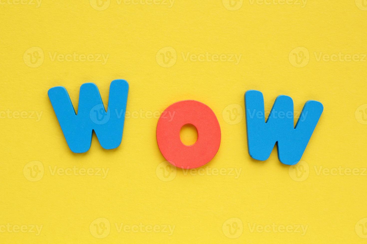 Word WOW colored letters on yellow background. Positive, happy, fun concept. Flatlay, top view photo