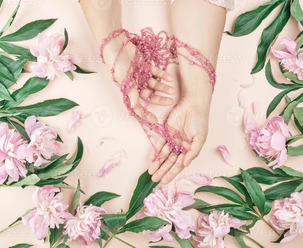 hands of a young girl with smooth skin and a bouquet of pink peonies photo