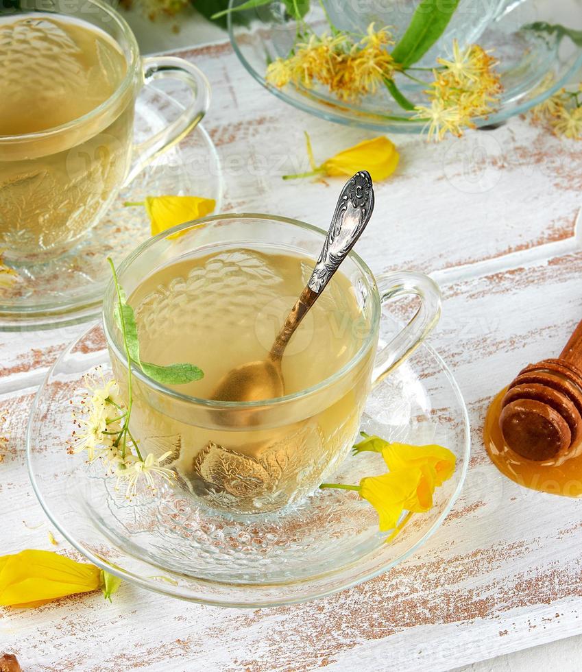 transparent cup with tea from linden on a white wooden board photo