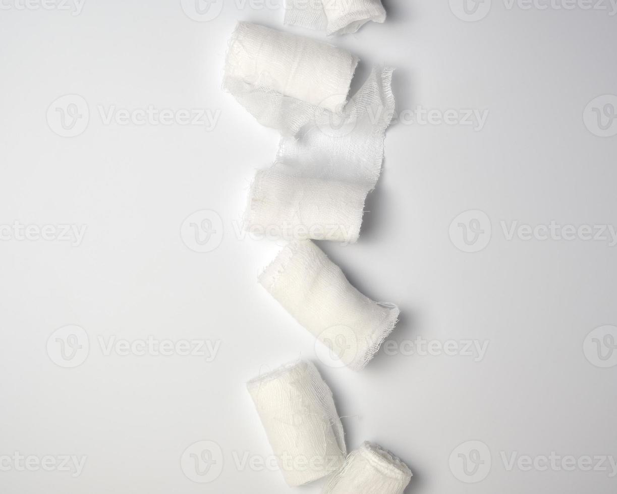 rolled up white sterile medical bandages on a white background photo
