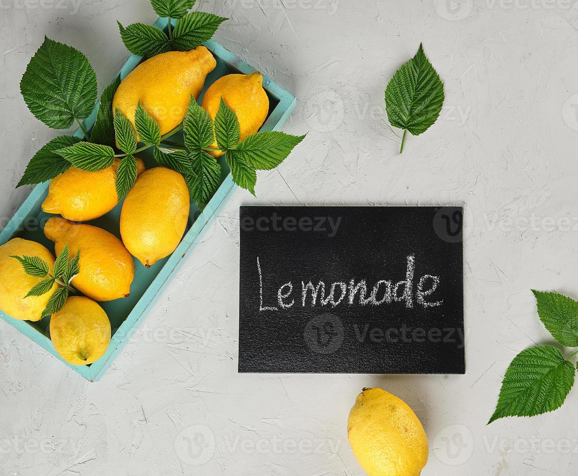 fresh ripe whole yellow lemons and black frame with an inscription lemonade photo