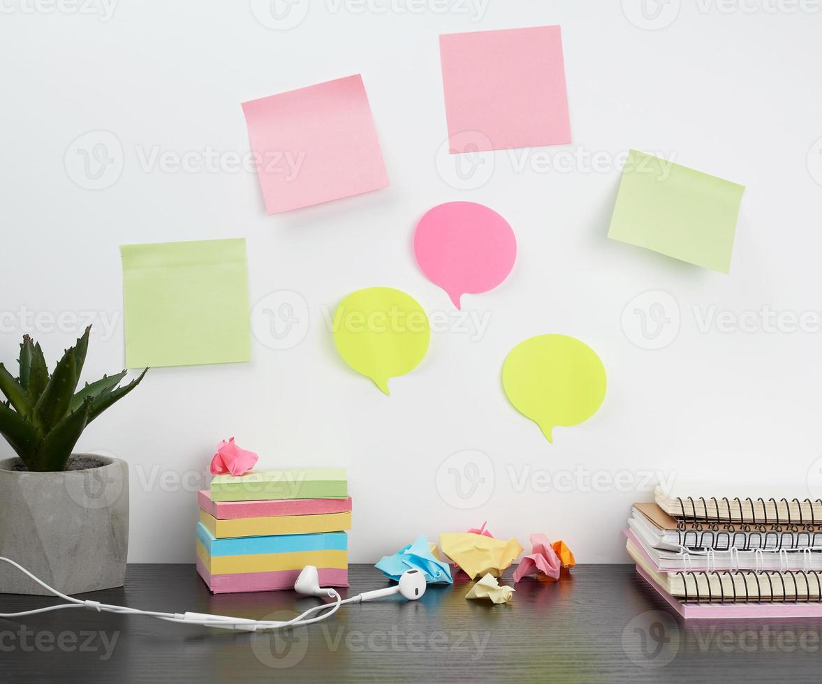 colored stickers attached to a white wall, on the table a stack of notepads photo