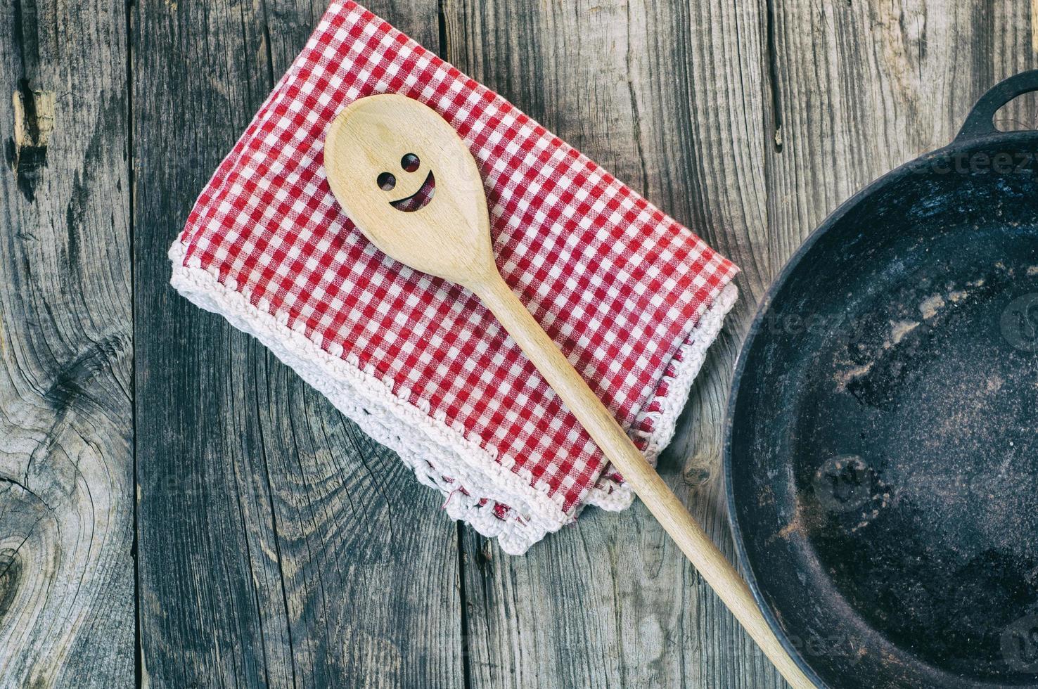 Black cast-iron frying pan with a wooden spatula for stirring photo