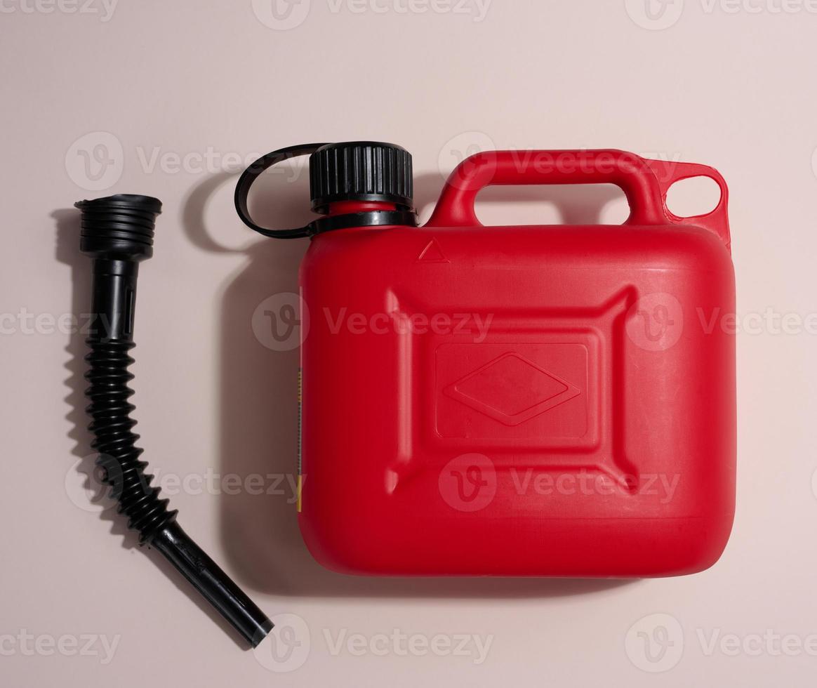 Red plastic canister for liquid fuels and lubricants on a beige background photo