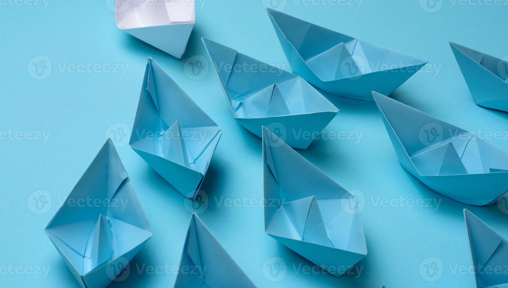 group of blue paper boats follow white against a light blue background. Strong leader concept, mass manipulation. Starting a business with a well-coordinated team, start-up photo