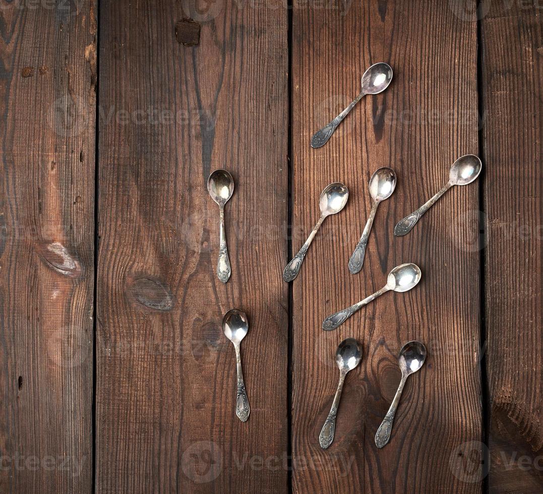 set of small metal teaspoons on a brown wooden table, top view photo