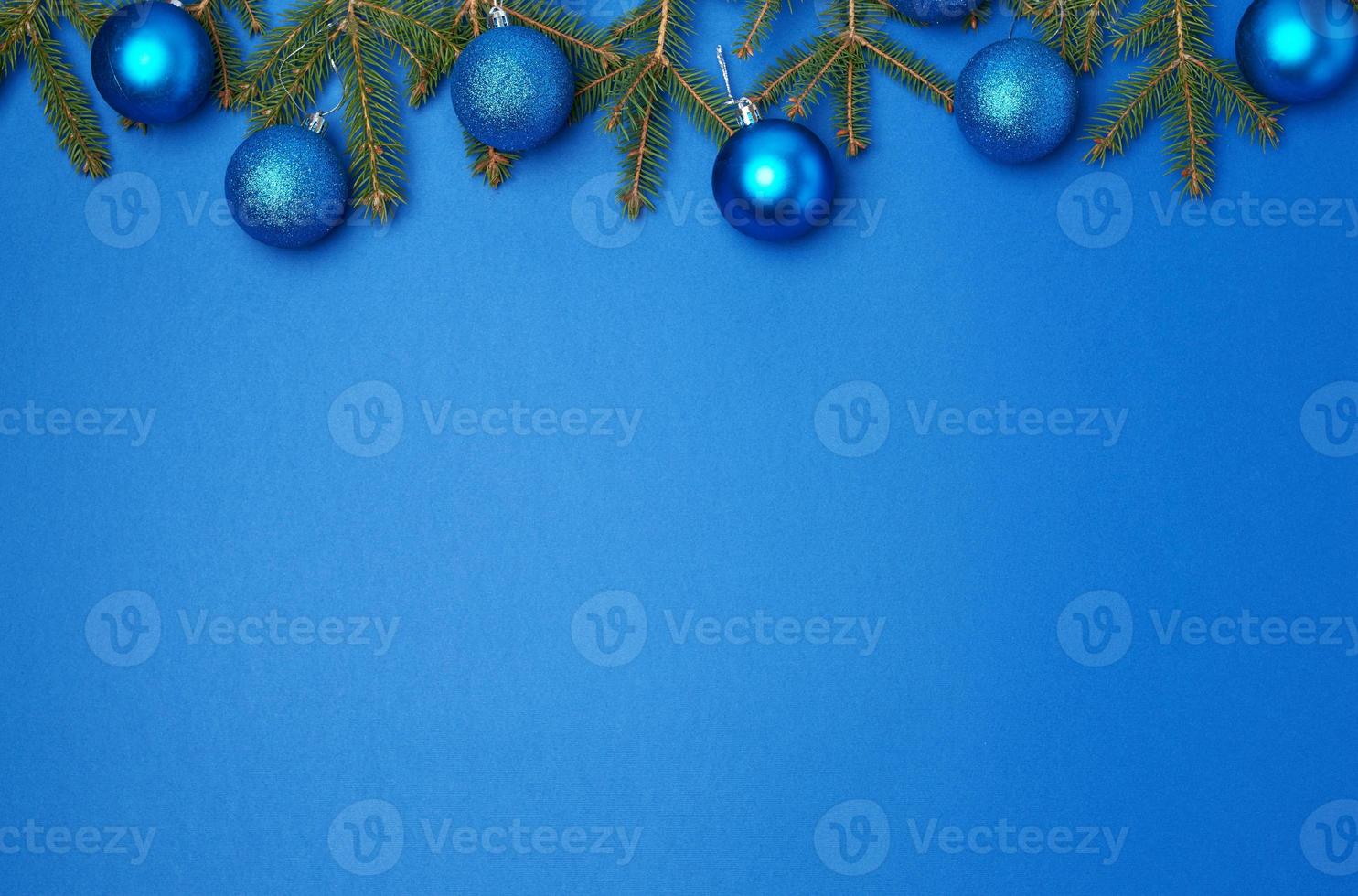 green spruce branches, blue shiny Christmas balls on a blue background, festive backdrop photo