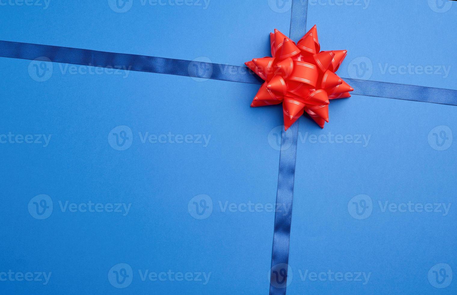 blue silk ribbon crossed on a dark blue background in the middle of a red bow photo