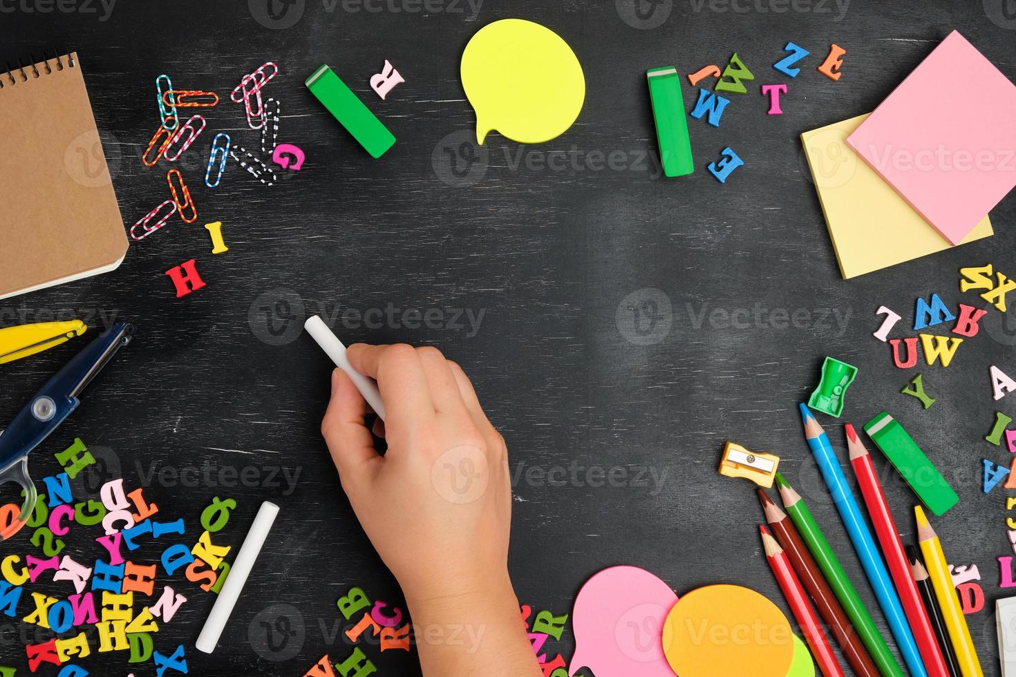 female hand writes with a white chalk on a blackboard photo