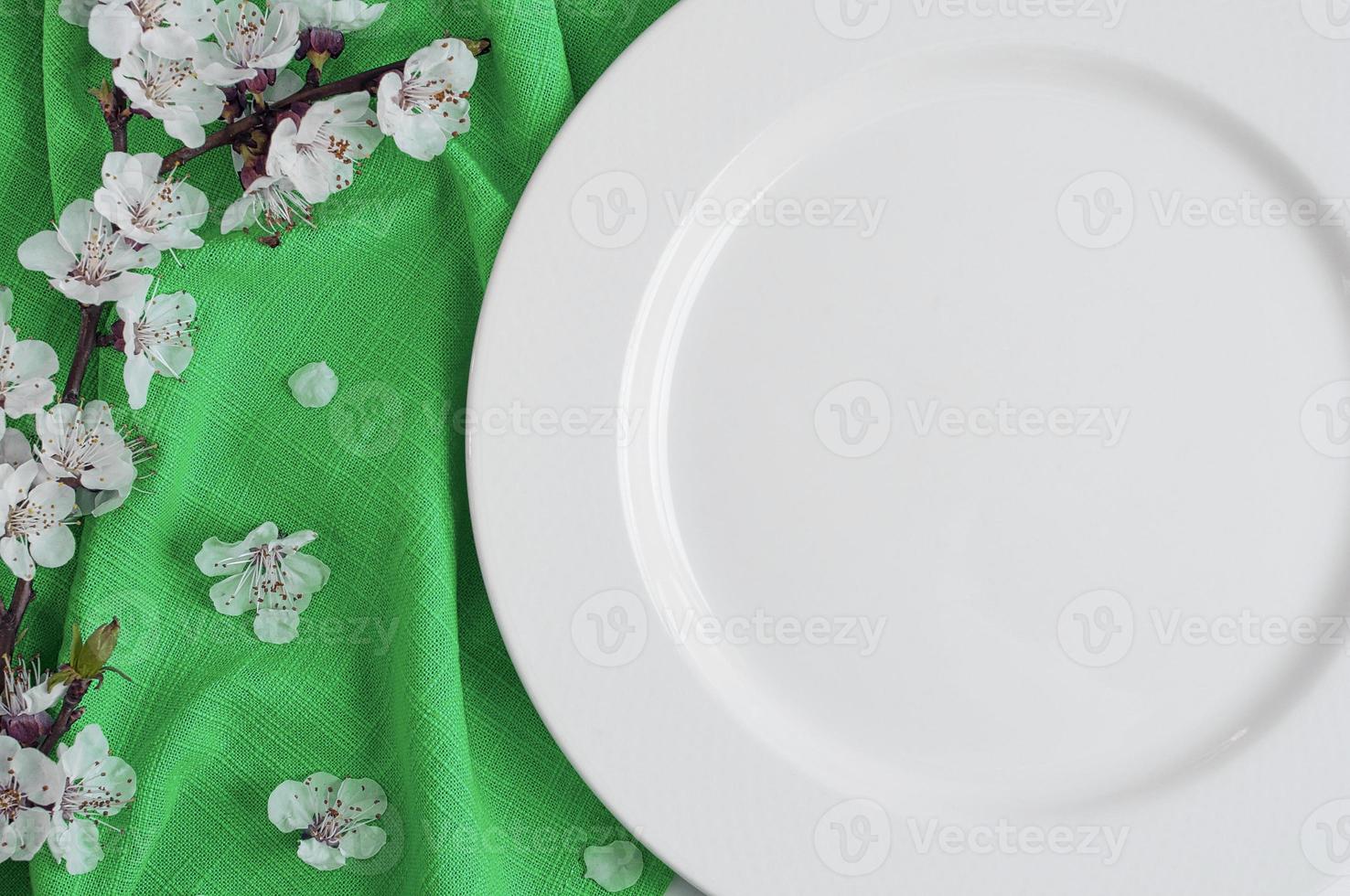 plato blanco vacío en una servilleta verde con flores de cerezo foto