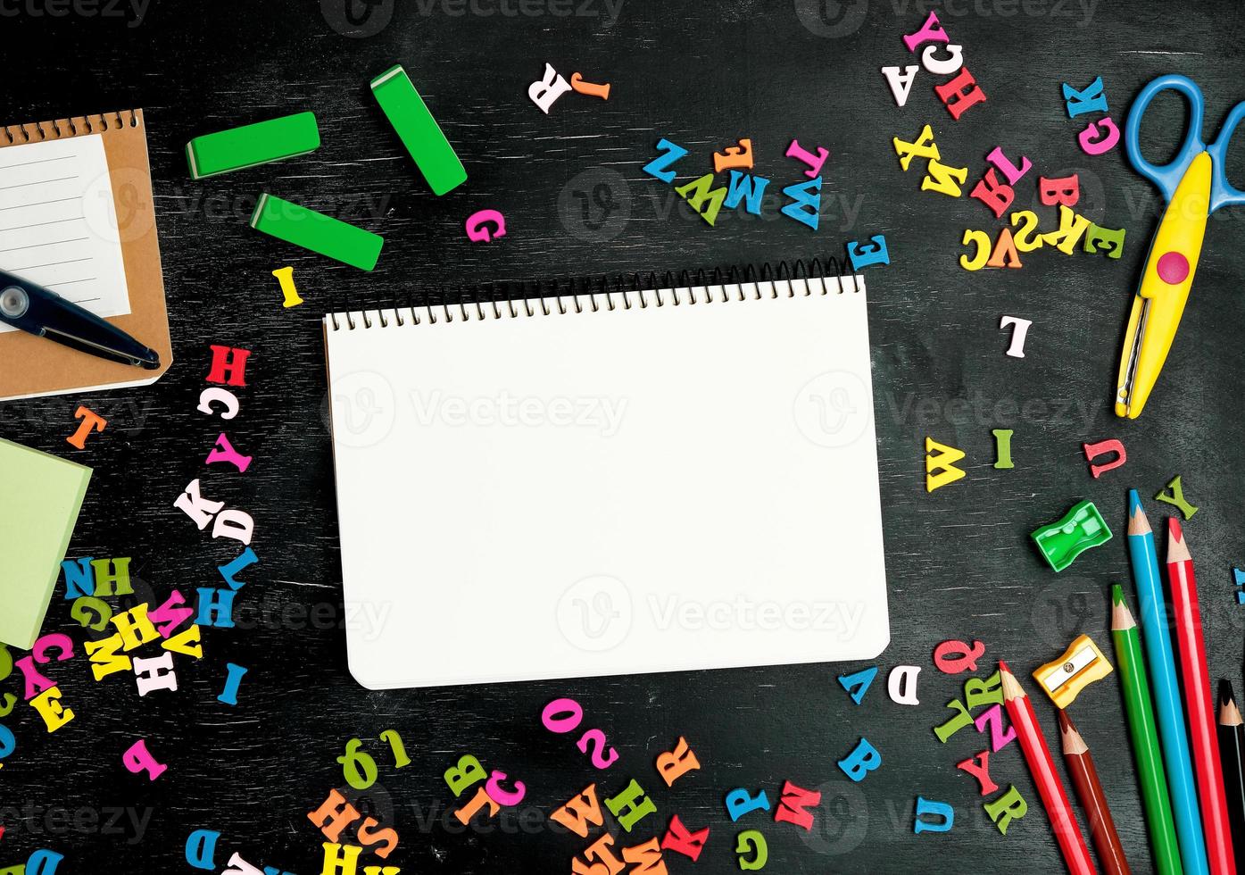 open spiral notebook with clean white sheets, wooden colored pencils photo