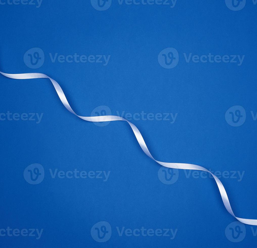 white silk thin ribbon twisted on a blue background photo