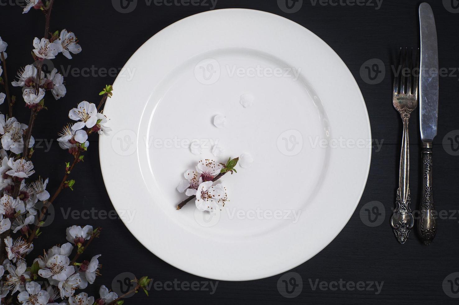 plato blanco vacío con cubiertos sobre una superficie de madera negra foto