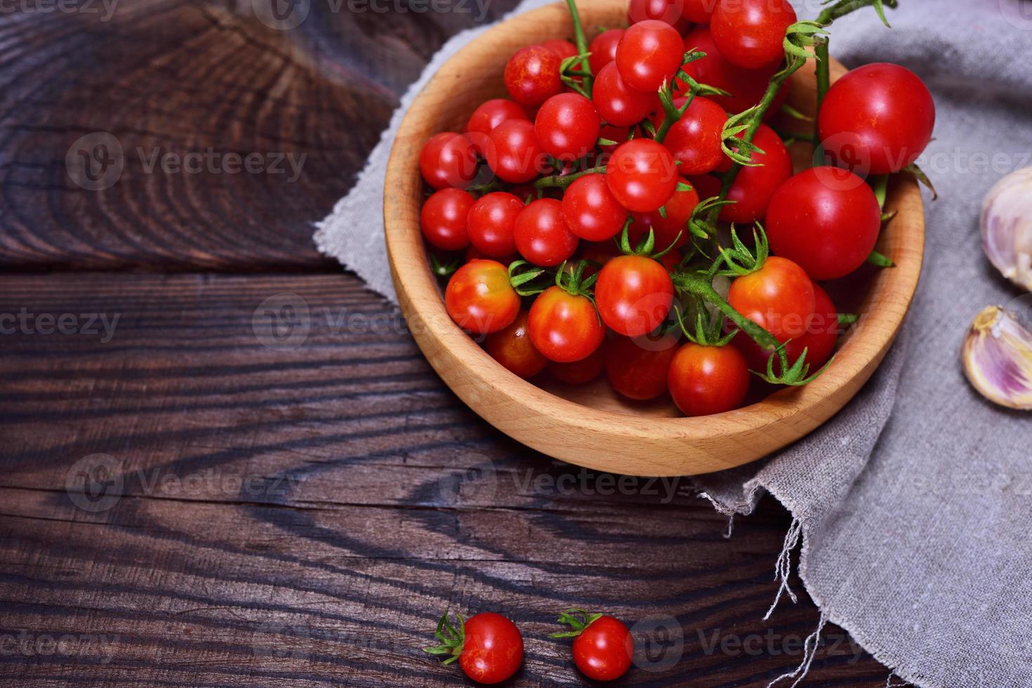 tomates cherry rojos frescos en un plato de madera foto