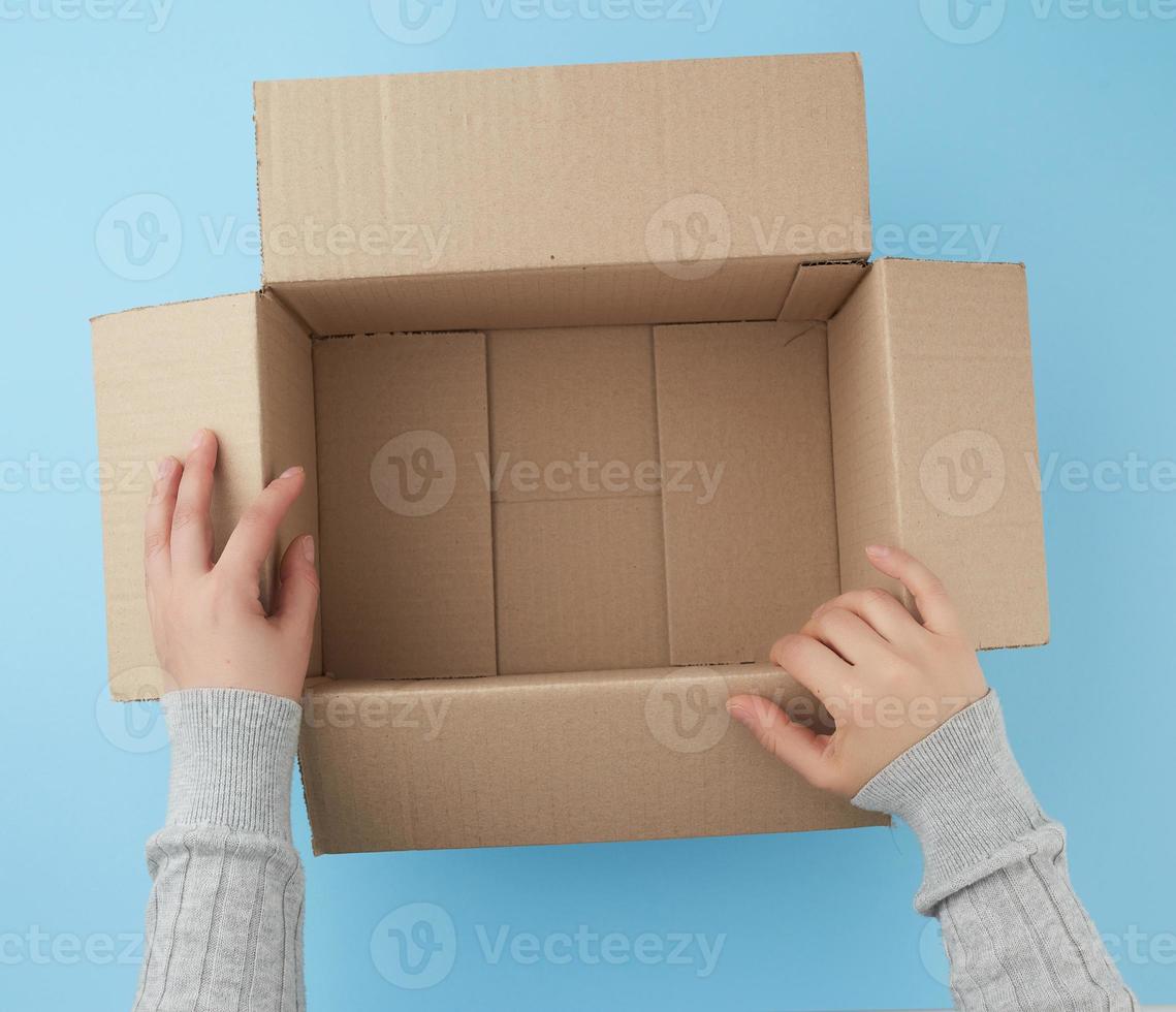 manos femeninas sostienen una caja abierta vacía de cartón marrón foto