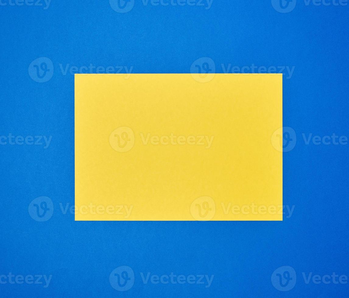 blank yellow sheet of A4 paper on a blue background photo