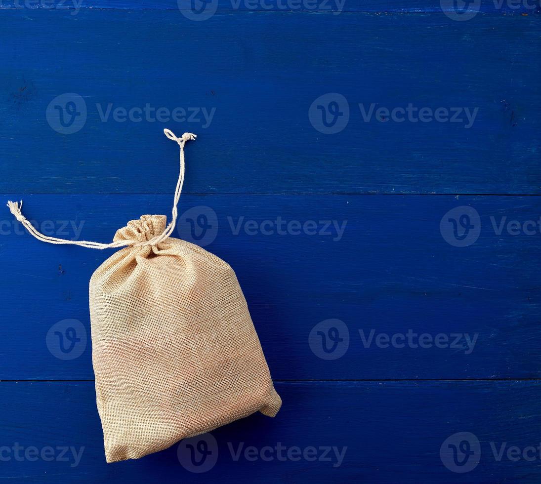 small full canvas bag with ties, blue wooden background photo