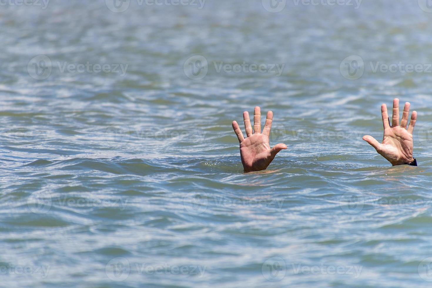 pair of masculine hands sticks out of the sea water photo