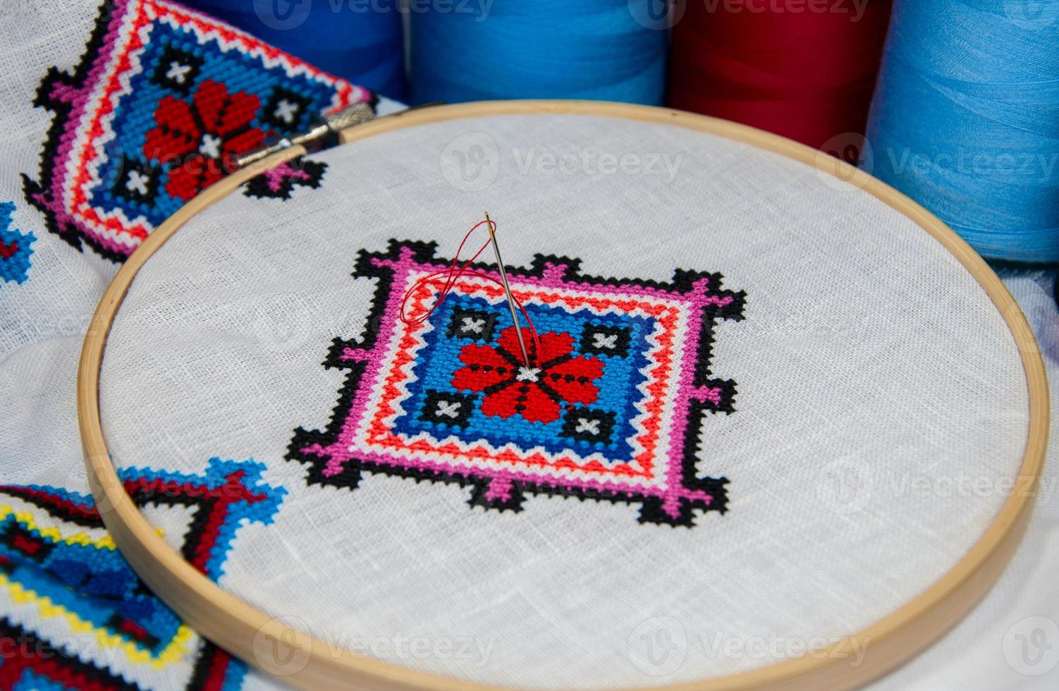 Traditional folk geometric pattern embroidered cross on a white cloth photo