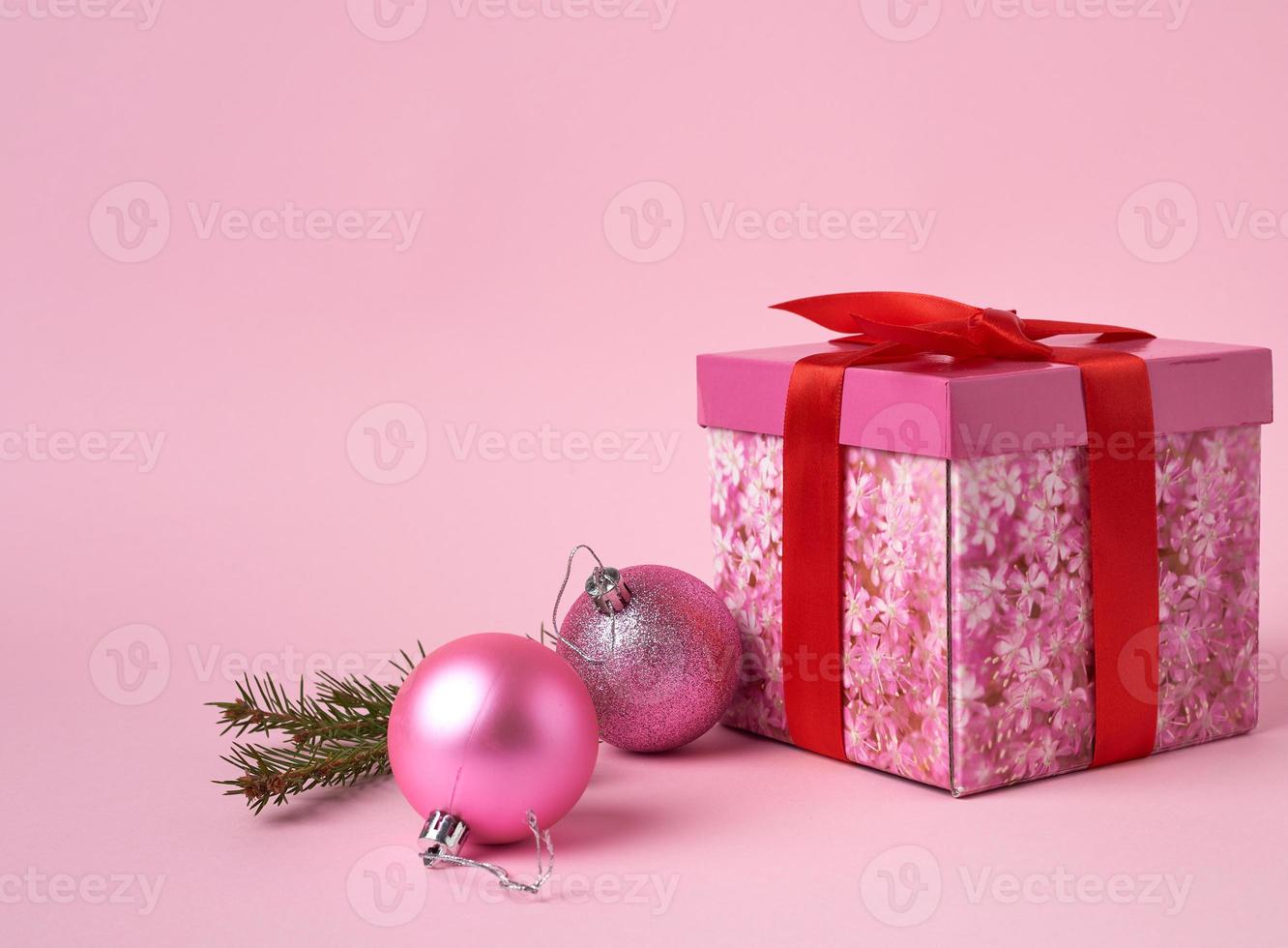 pink gift box with bow, green spruce branch and two decorative pink balls photo