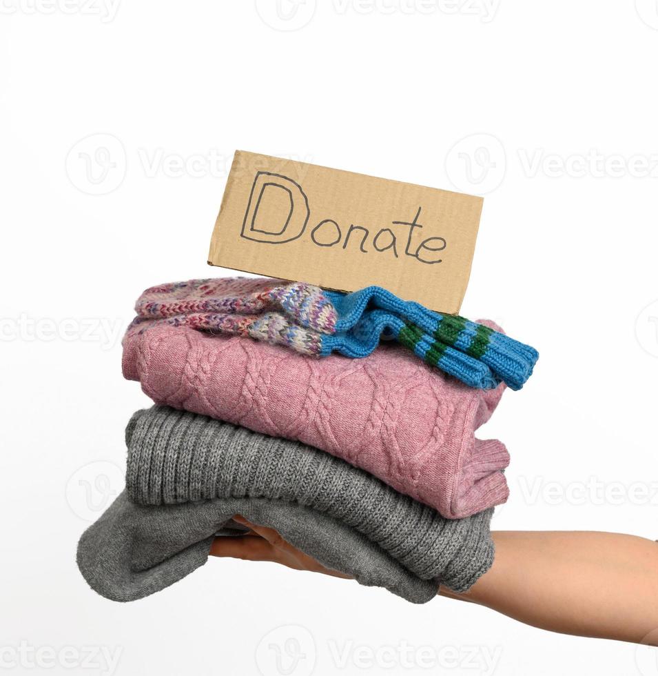 female hand holding a stack of clothes, help and volunteering concept, donation photo