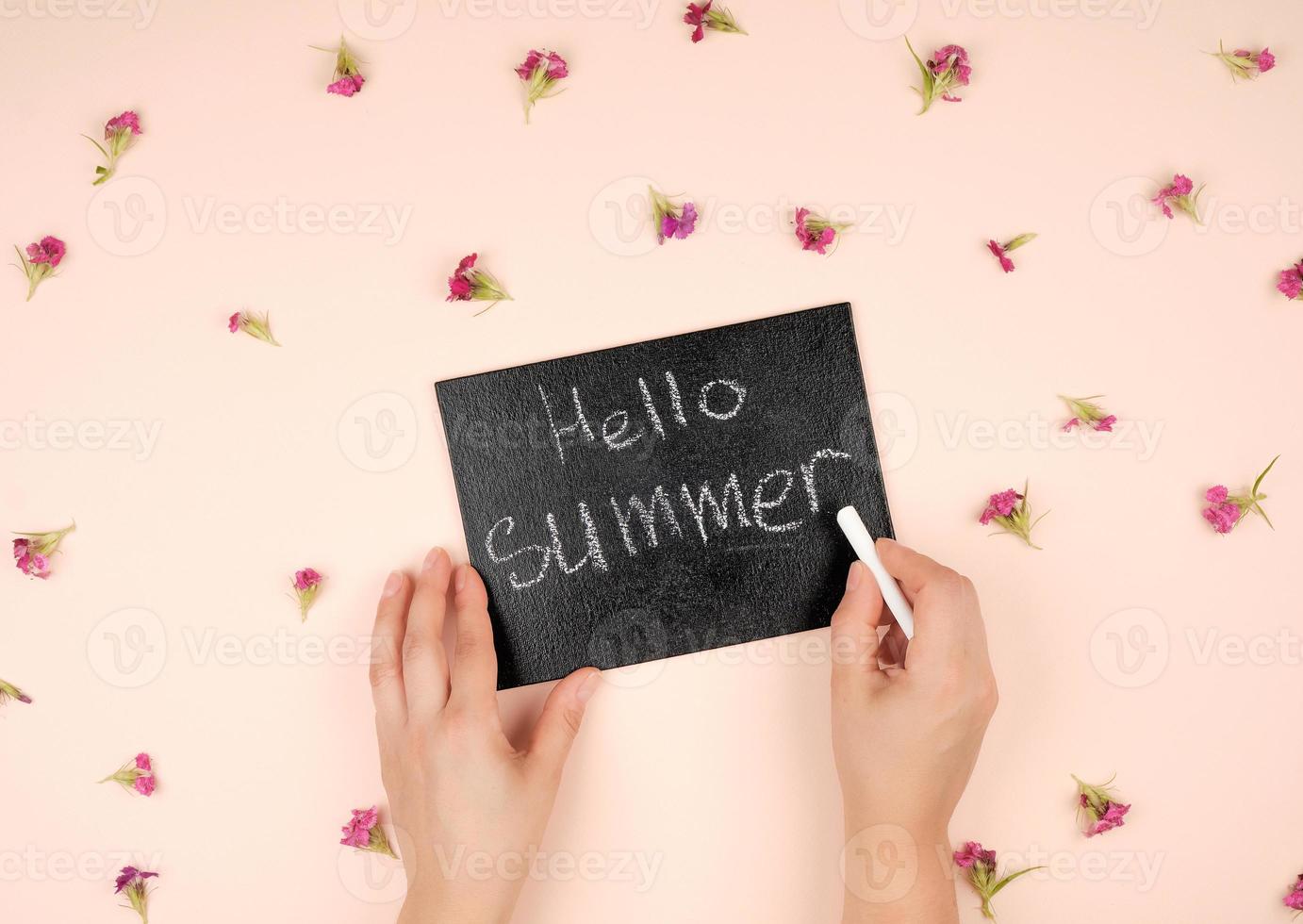 black chalk frame with an inscription hello summer and two female hands photo
