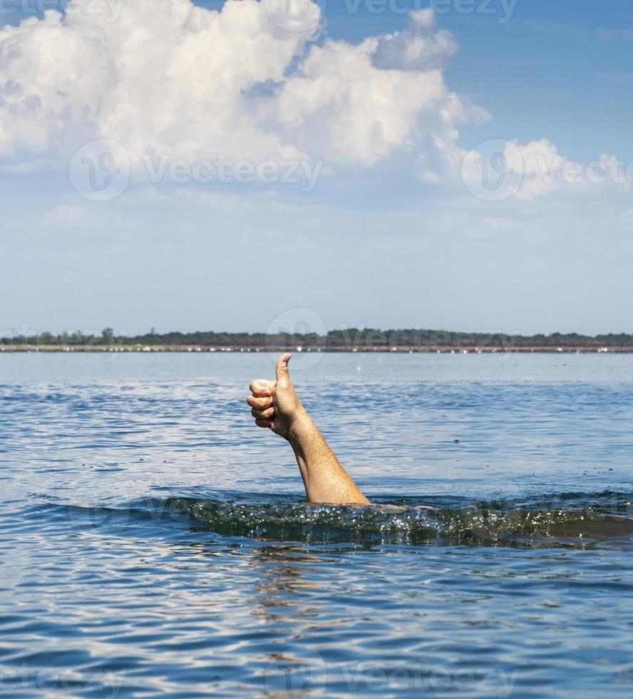 hand sticks out of the water and shows a gesture like photo