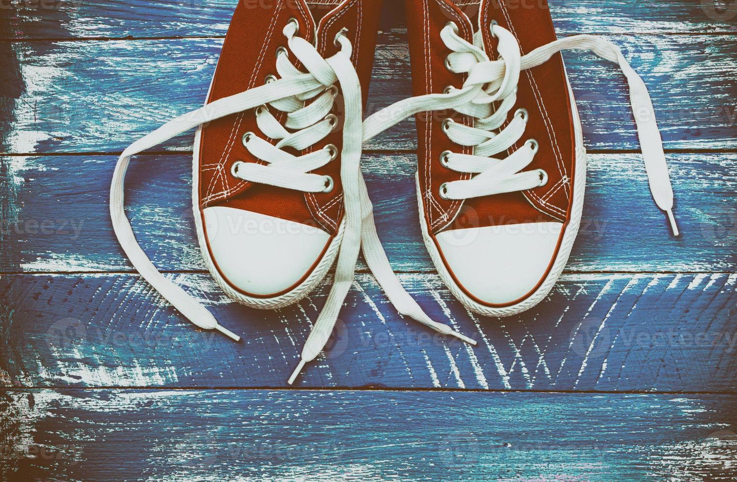 pair of red sneakers on a blue shabby wooden surface photo