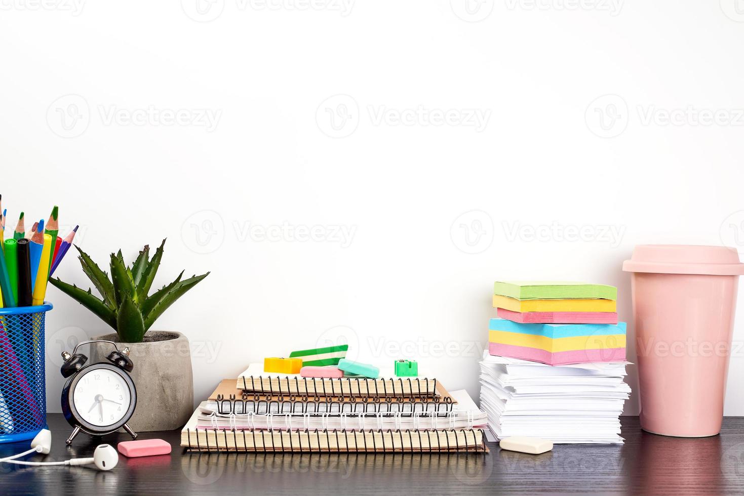 stack of spiral notebooks and colored stickers, next to a ceramic pot with a flower photo