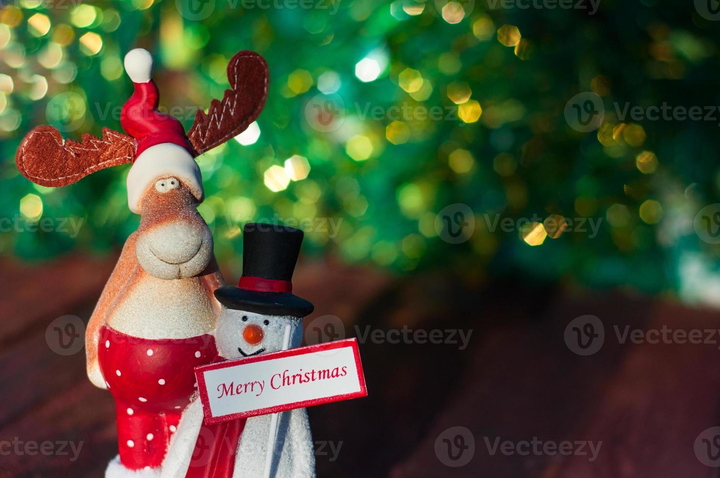 Christmas toy elk and snowman on green blurred background photo