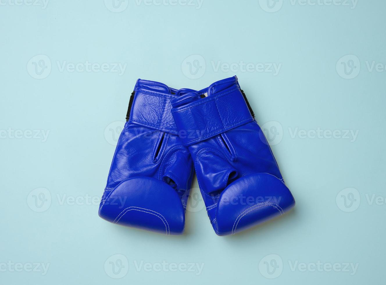 Blue leather boxing gloves on a blue background. Sports equipment, top view photo