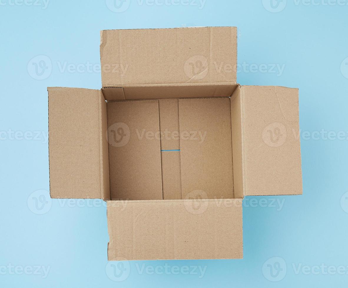 open square empty cardboard brown box for packing and shipping things on a blue background photo