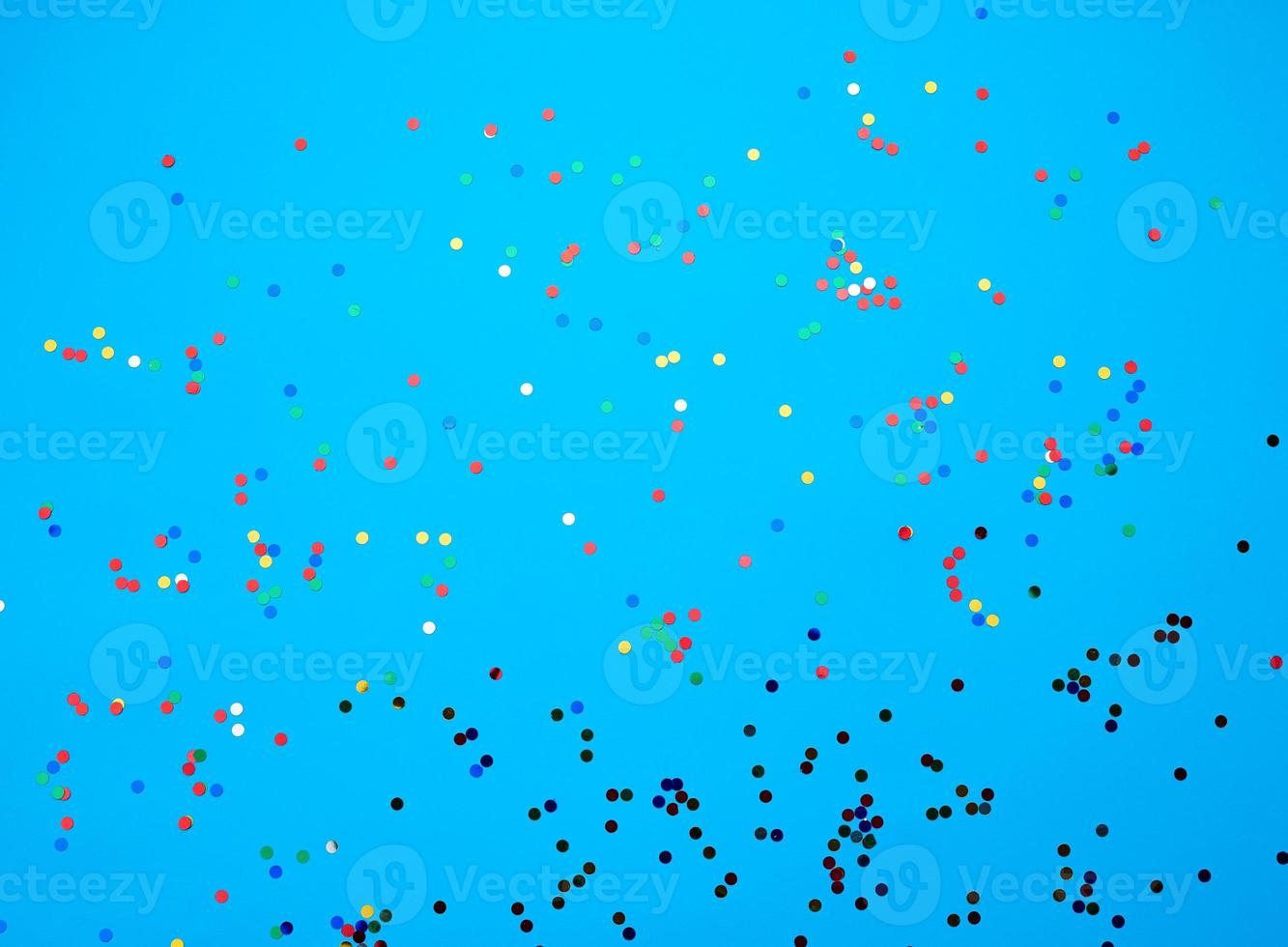 shiny multicolored round confetti scattered on a blue background photo