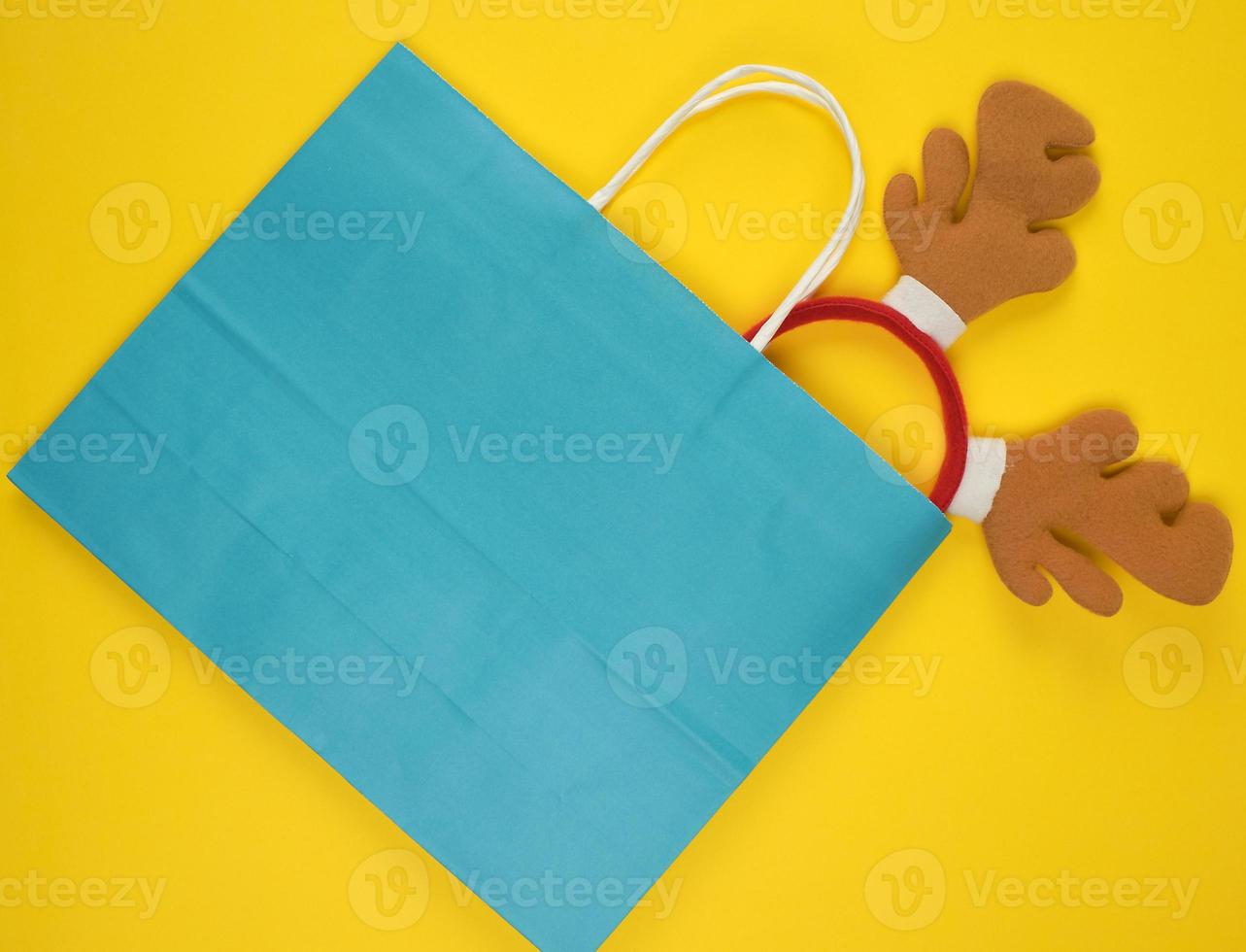 bolsas de papel para ir de compras, dentro de la máscara navideña de un ciervo sobre un fondo amarillo foto