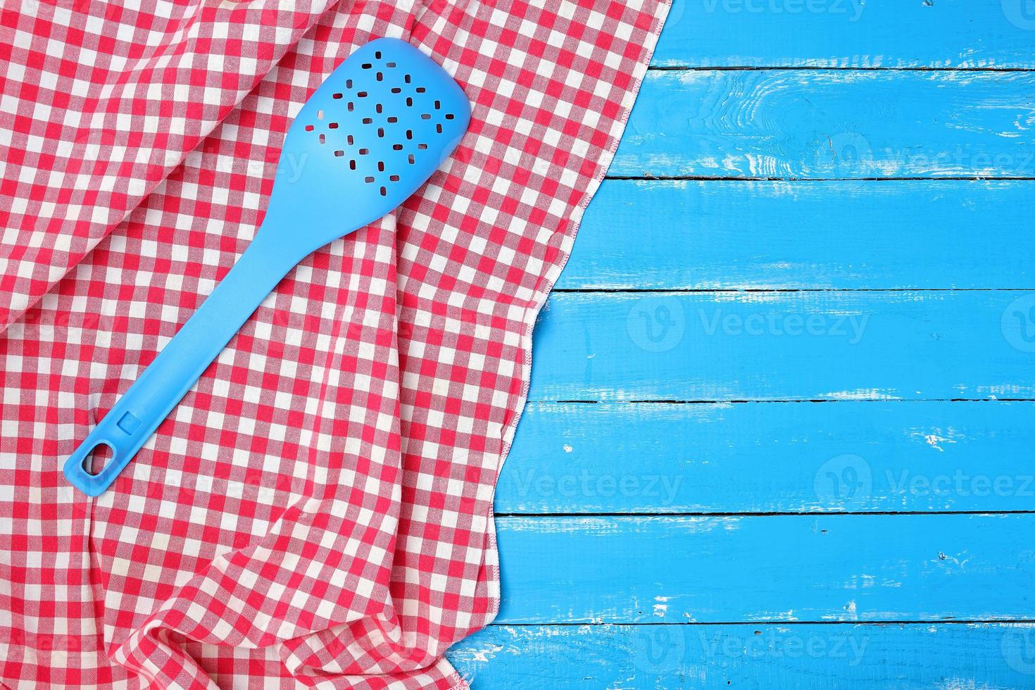 plastic blue spoon with holes on a red textile napkin photo