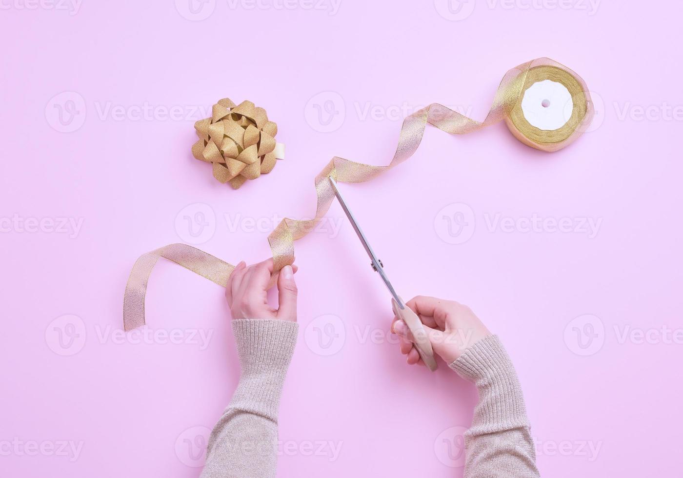 female hands cut golden ribbons in a roll for packing gifts photo