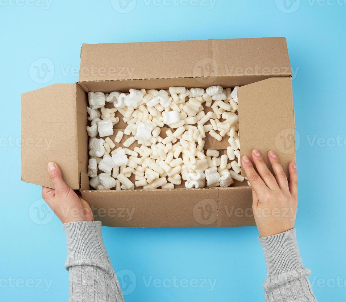 two female hands hold an empty open box of brown cardboard photo