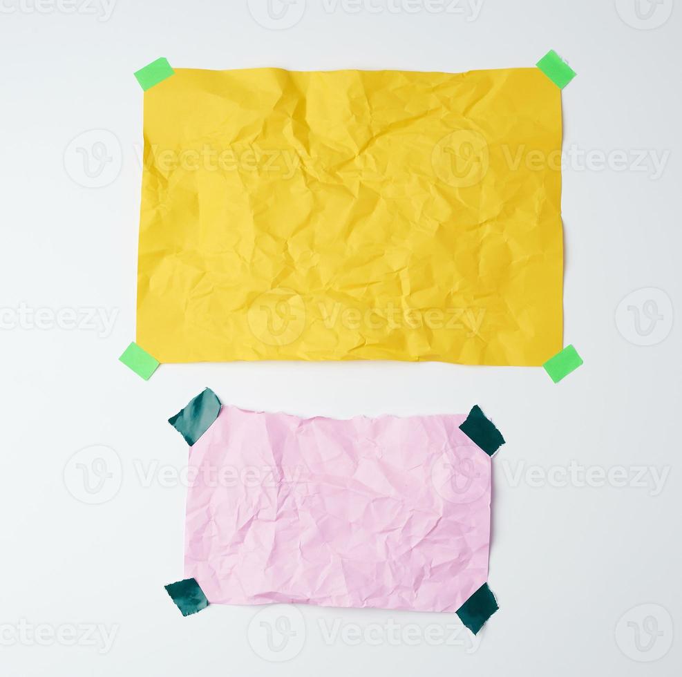 empty yellow and pink crumpled sheets of paper glued with green sticky pieces photo