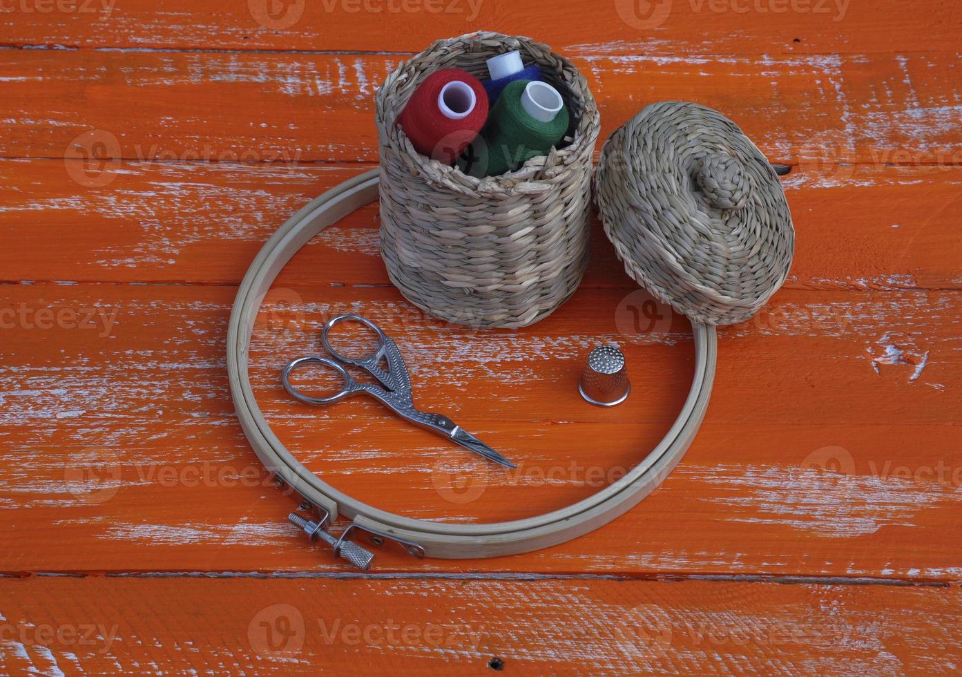 Spools of thread in a wicker basket and items for needlework photo